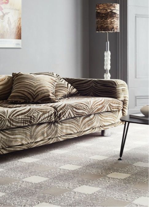 A zebra print sofa is placed on a square patterned grey and beige carpet